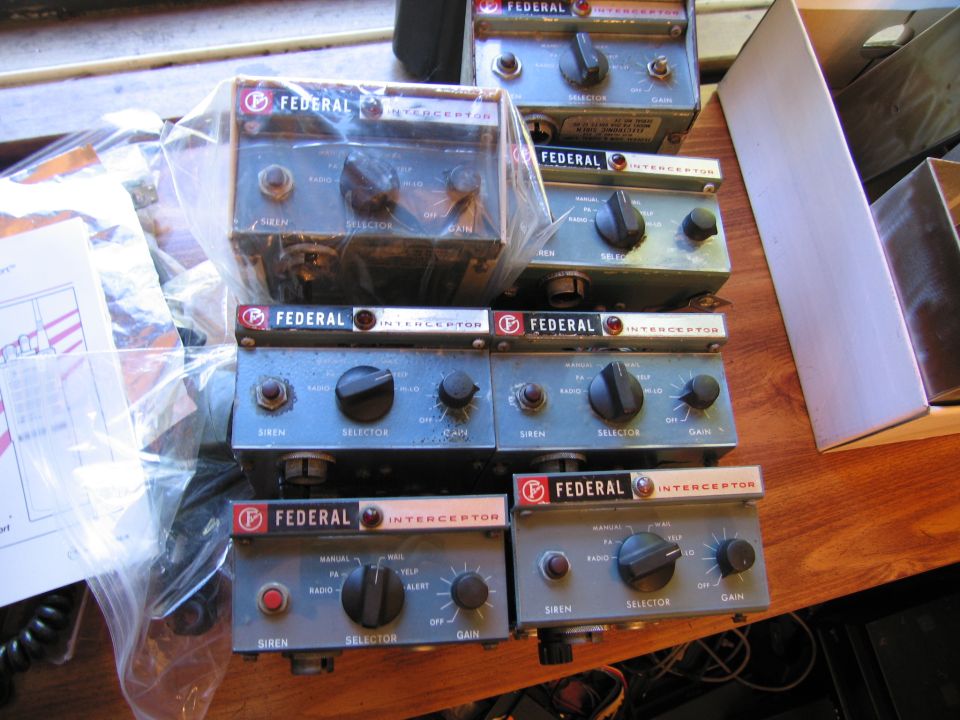 Several vintage Federal Interceptor siren control heads arranged on a wooden bench
