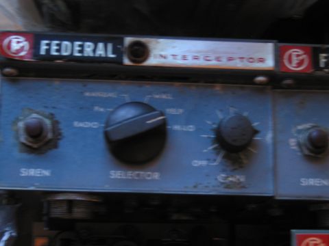 1991 Ford LTD Crown Victoria - weathered, dimly lit Federal Interceptor siren control panel shows its selector and gain knobs and faded labeling.