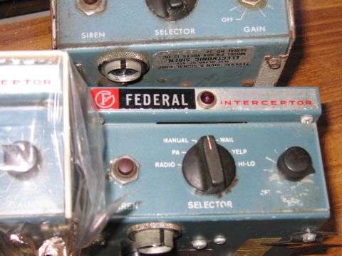 1991 Ford LTD Crown Victoria - blue Federal Interceptor siren control head sits among others, with a metal model and serial number label visible above it.
