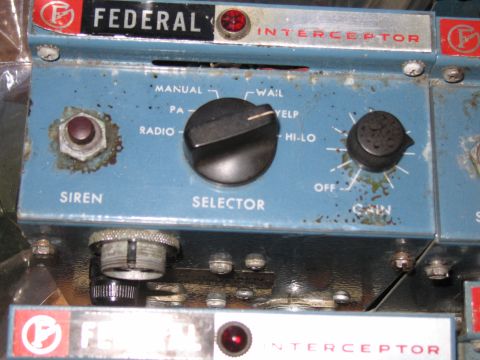 1991 Ford LTD Crown Victoria - rusty blue Federal Interceptor siren control head shows corrosion around the selector and gain knobs, with another unit below it.