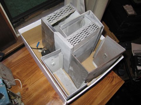 1991 Ford LTD Crown Victoria - Several bare galvanized metal chassis enclosures with vented panels sit inside a white cardboard box on a wooden table.