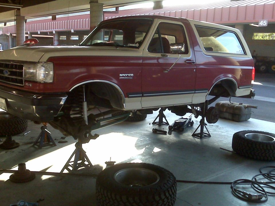 1989 Ford Bronco on jack stands in a garage, undergoing maintenance