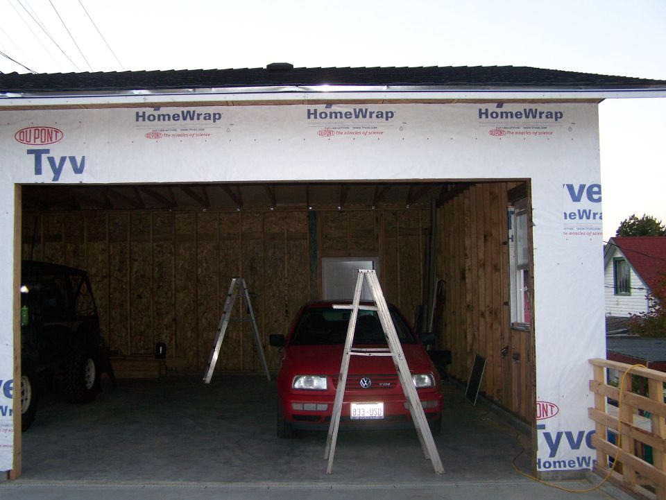 Red Volkswagen Golf parked inside a Tyvek-wrapped garage under construction