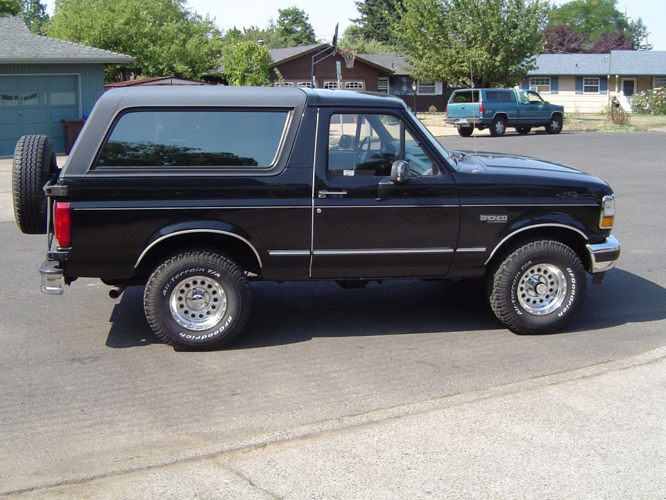Black 1989 Ford Bronco parked on a street, side view, with BFGoodrich All-Terrain T/A tires.