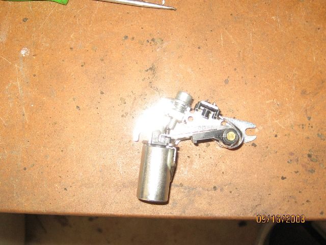 Metal ignition points assembly on a wooden workbench.