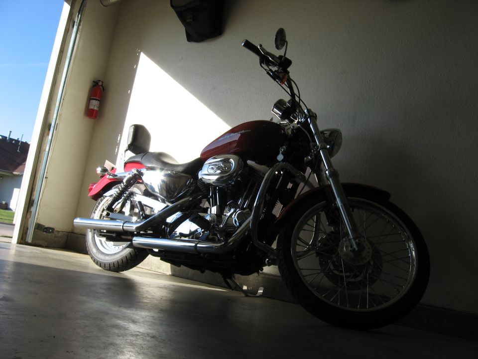 Red Harley-Davidson Sportster motorcycle parked in a garage.