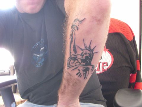 1978 Ford Bronco - A person's arm with a tattoo of the Statue of Liberty is shown in front of a person wearing a black and red jersey.
