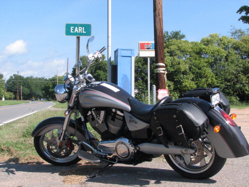 Silver Victory cruiser motorcycle parked beside a green EARL street sign