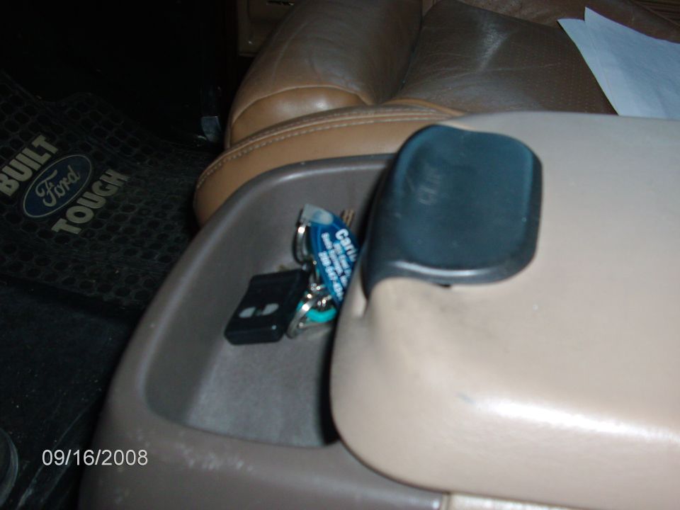 Tan center console cupholder with keys and remote fob, Built Ford Tough floor mat at left