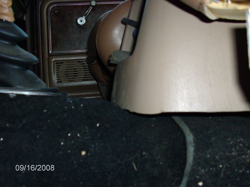 Interior of a vehicle showing floor carpet and center console.