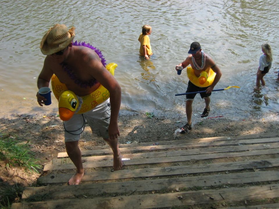 People with floats climbing wooden steps from a river bank