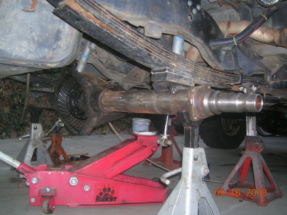 Vehicle undercarriage on jack stands showing rear axle and driveshaft