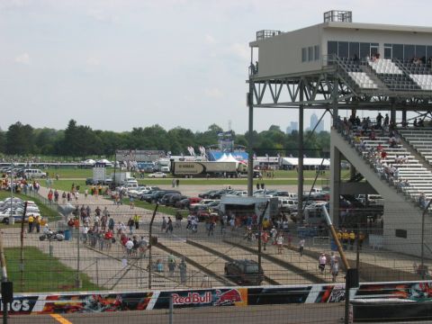 1985 Ford LTD Crown Victoria - Photograph of a racetrack paddock and crowd; not a technical document.