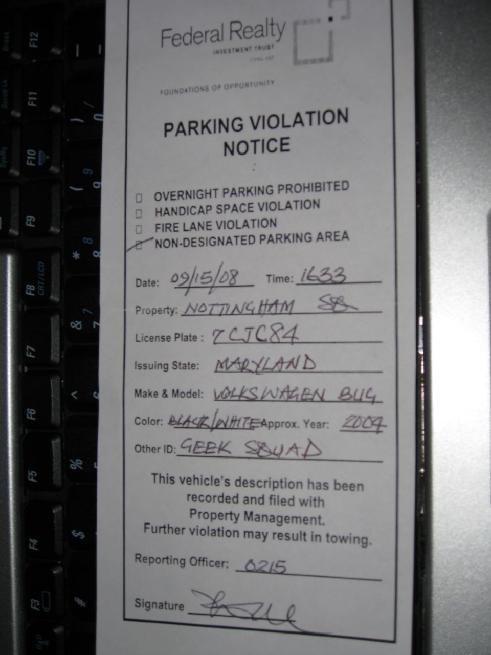 Handwritten parking violation notice on a keyboard from Federal Realty