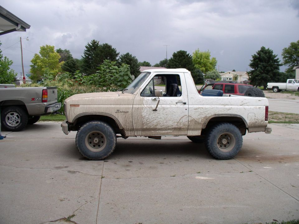Mud-covered tan and white Ford Bronco parked on a driveway