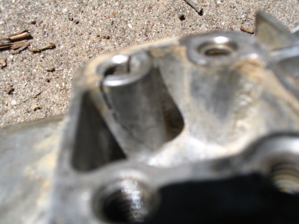 Close-up of a blurry metal vehicle part with a threaded hole.