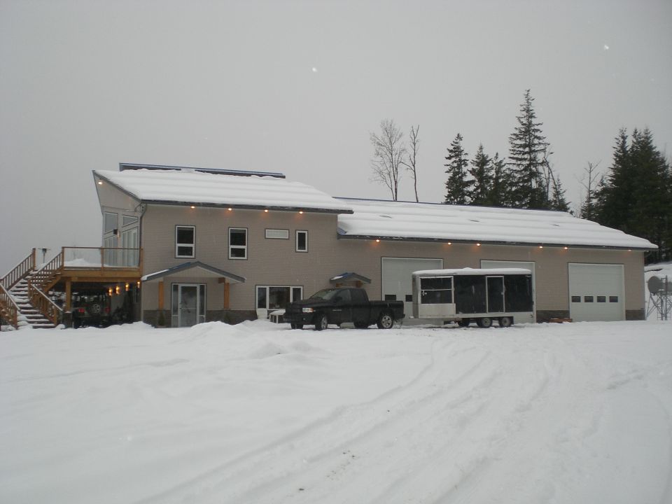 Black Dodge Ram pickup and enclosed trailer parked at a snowy shop building