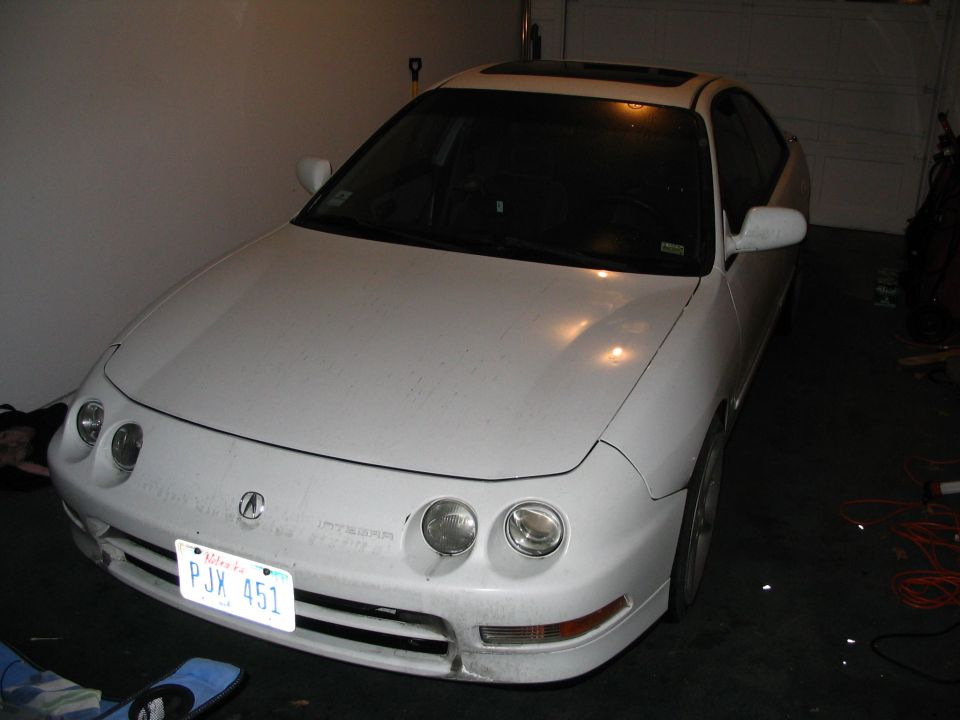 White Acura Integra with quad round headlights parked in a garage, front three-quarter view