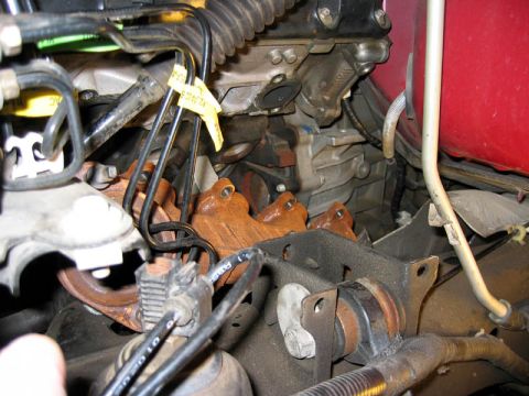 2007 Ford Mustang - Photograph of an engine bay area with exhaust manifold, vacuum lines and brackets, a physical view not a diagram.