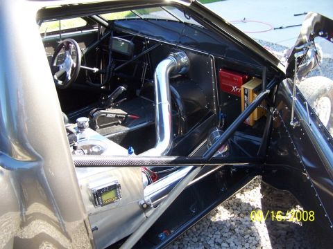 2007 Ford Mustang - Photograph of a stripped race-car interior with roll cage, gauges and battery, a vehicle photo not a document.