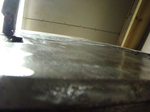 1948 Jeep Wrangler - A close-up view of a metal surface, possibly part of a vehicle body, with a wall visible in the background.