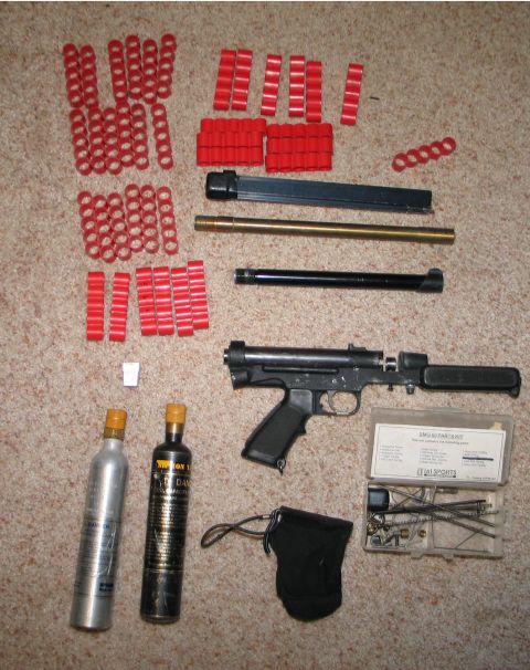 1994 Ford Bronco - Various airsoft gun components, including a receiver, barrels, CO2 cartridges, and loading clips, are laid out on a carpeted surface.