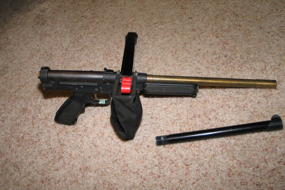 Airsoft gun with magazine inserted, brass barrel attached, and a separate black barrel piece