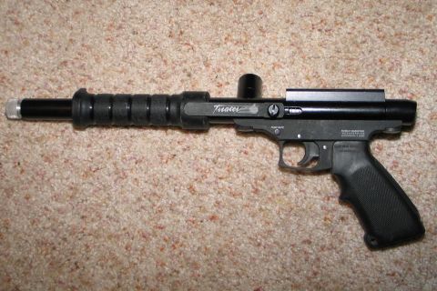 1994 Ford Bronco - A black paintball gun with a textured grip and "Tracer" branding is shown on a carpeted surface.