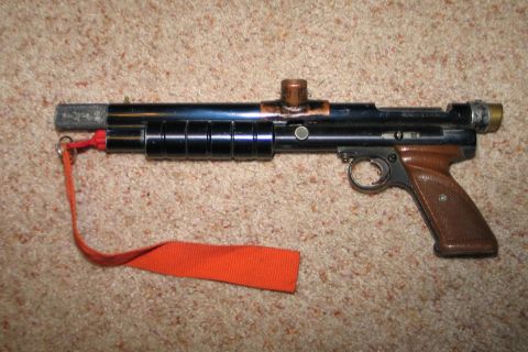 1994 Ford Bronco - Air gun with wooden grip and orange lanyard on carpet.