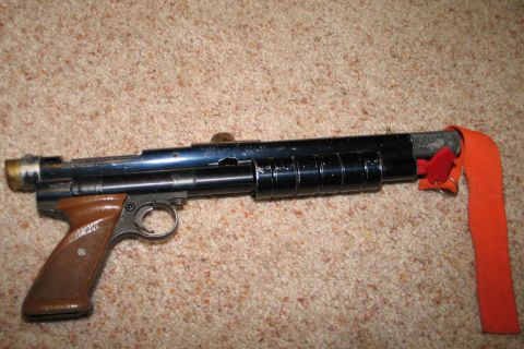 1994 Ford Bronco - An air gun rests on a carpeted surface, showing its metallic barrel and brown grip.