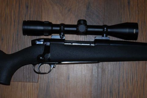 1991 Ford Bronco - A close-up view of a rifle with a scope mounted on top, resting on a wooden surface.