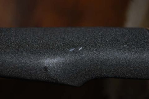 1991 Ford Bronco - A textured black surface, possibly a car part, shows two small white marks.