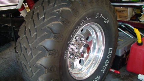 1979 Ford F-250 - A close-up view of a large, aggressive off-road tire and its shiny chrome wheel, with a red gas can visible in the background.