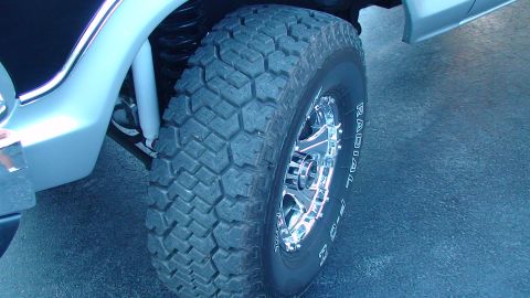 1979 Ford Bronco - A close-up view of a tire and chrome wheel on a vehicle, possibly modified, silver SUV.