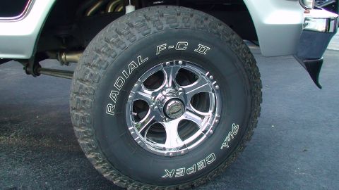 1979 Ford Bronco - A close-up view focuses on a modified off-road tire and chrome wheel assembly on a vehicle.