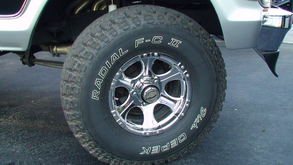 Close-up of a large off-road tire with chrome wheels and "Dick Cepek" lettering