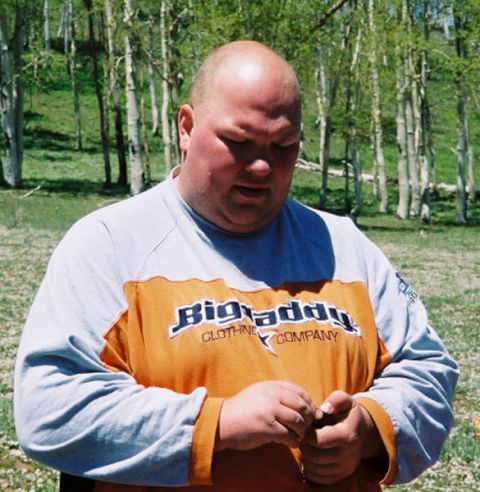 1996 Ford Bronco - A man wearing a long-sleeved shirt with text stands outdoors among trees.