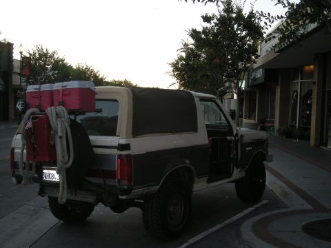 1991 Ford Bronco - This 1991 Ford Bronco is parked on a street with its doors open and camping gear on the back.