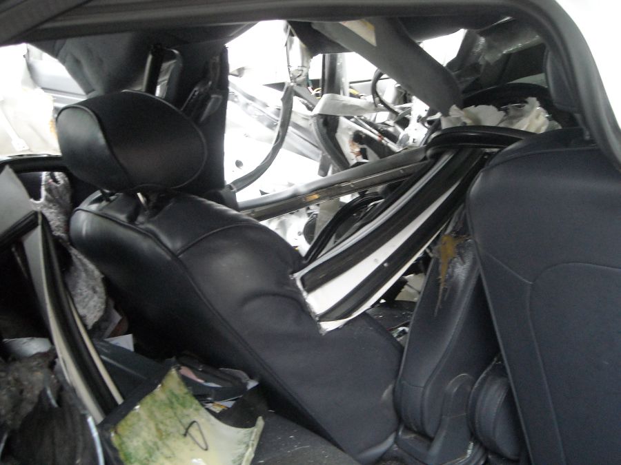 Interior of a wrecked car showing torn metal, exposed wires, and damaged seats