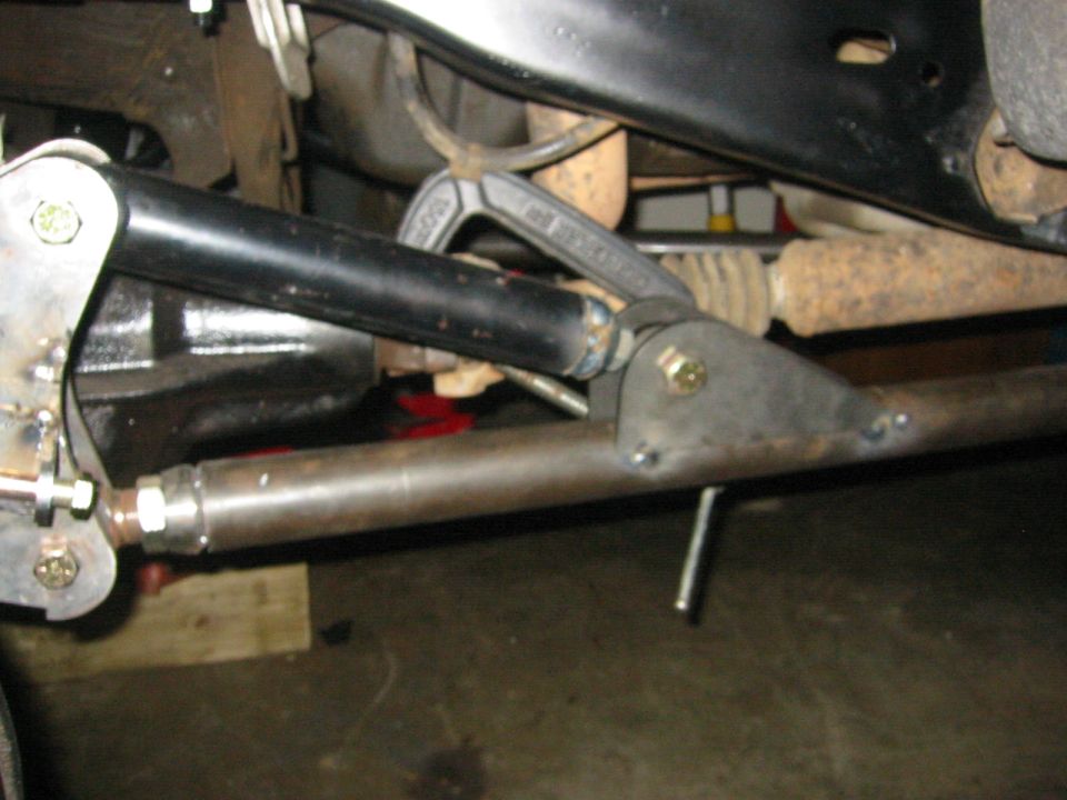 Close-up of vehicle front suspension with metal rods, bolts, and a clamp
