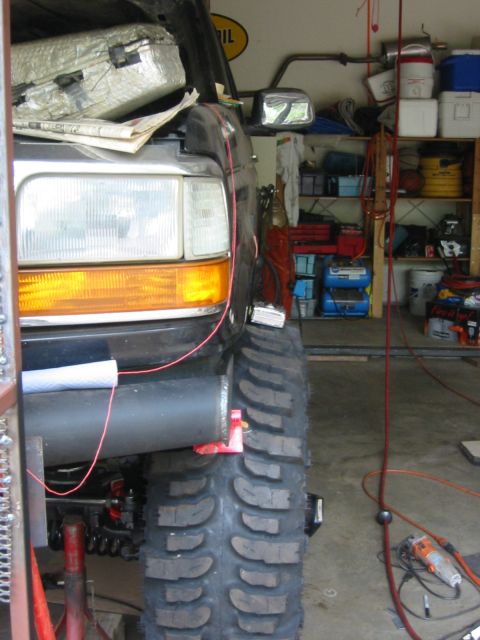 1995 Ford Bronco - A black Ford Bronco's front tire and fender are visible in a garage setting.