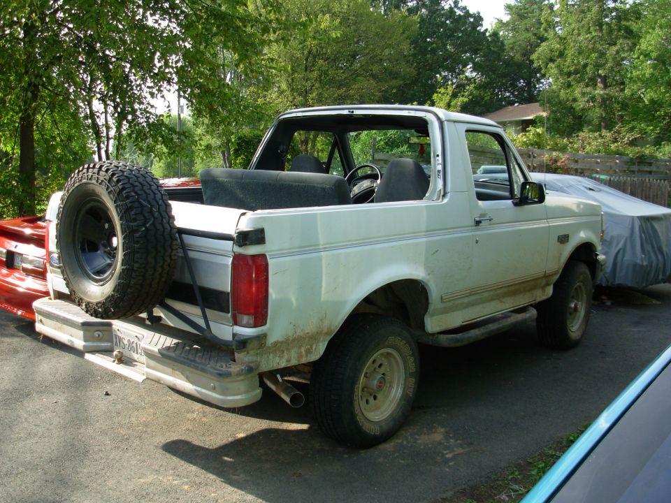 White Ford Bronco topless SUV rear view with spare tire on chrome bumper