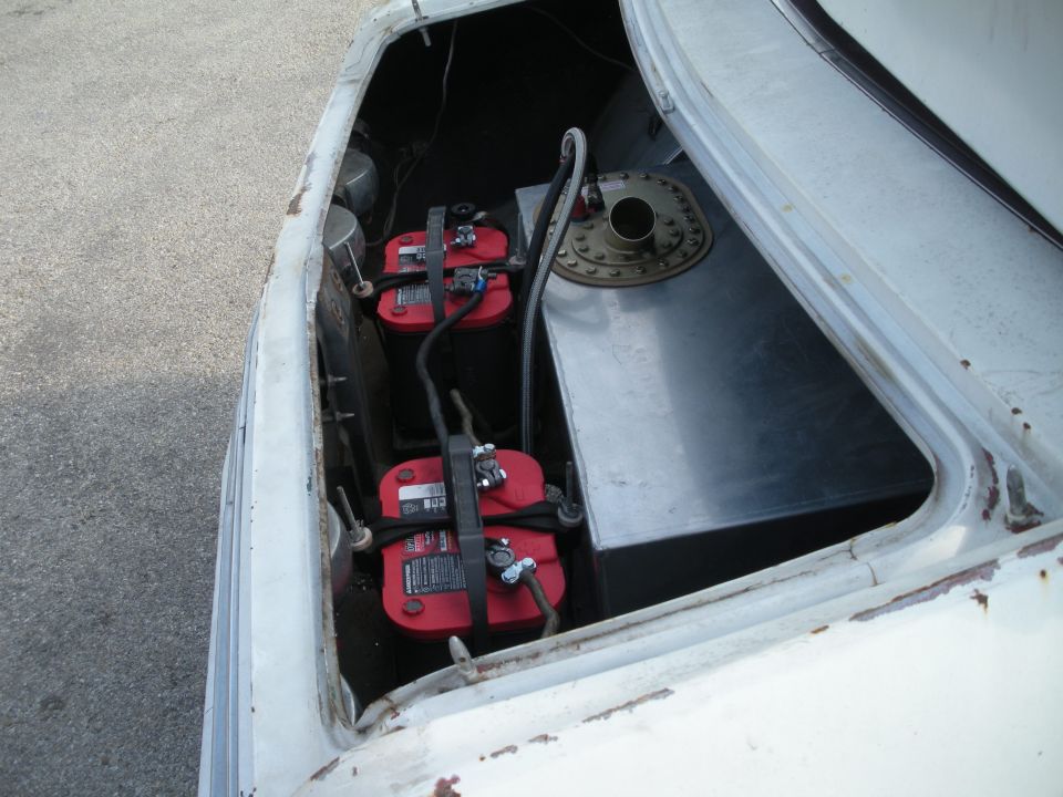 Car trunk with two red Optima batteries and a metal fuel cell. The car is white and appears to be older