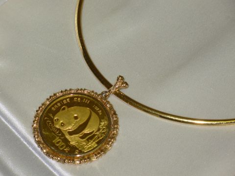 2004 Land Rover Land Rover - A gold panda coin pendant is shown on a gold necklace against a white satin background.