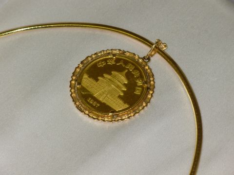 2004 Land Rover Land Rover - A close-up of a gold panda coin pendant, Chinese inscriptions and a building motif, dated 1987.