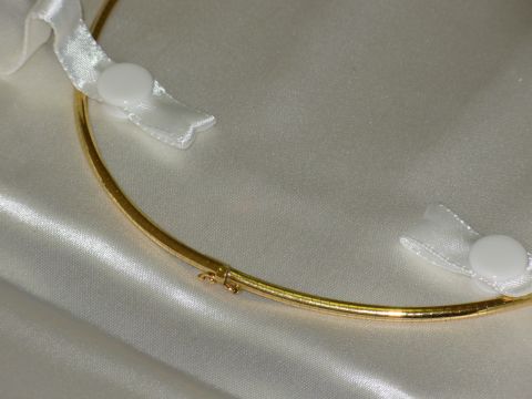 2004 Land Rover Land Rover - A gold necklace with white ribbon bows is displayed on a satin background. The image contains text from Supermotors.net.