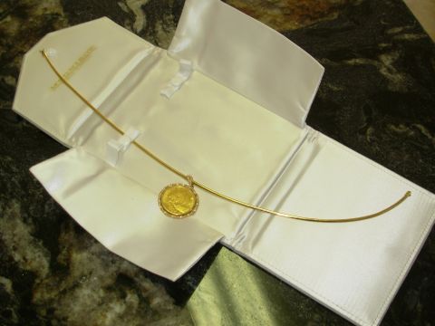2004 Land Rover Land Rover - A panda coin necklace is displayed on white paper, with a gold-colored charm.