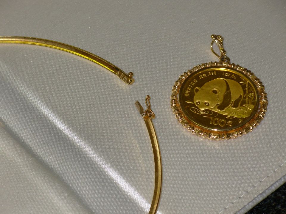Gold panda coin pendant with a necklace clasp. Text on coin reads '100元' and '1oz Au'