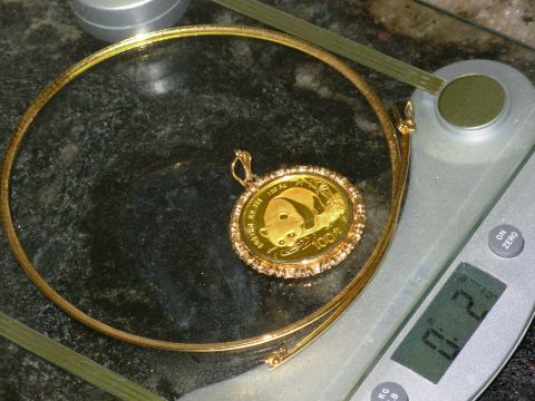 2004 Land Rover Land Rover - A gold panda coin pendant is displayed on a necklace, resting on a digital scale.