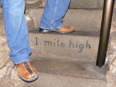 2006 Ford E350 - Stone steps are marked with '1 mile high' and show the lower legs and feet of two individuals wearing jeans and casual shoes.